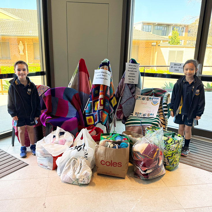 Students from Our Lady of The Rosary Primary School Kellyville who are part of the Parish Knitting Club standing with the blankets they've knitted for the needy