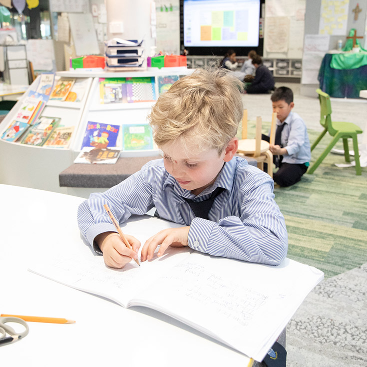 Student writing at his desk in the classroom at Our Lady of The Rosary Primary School Kellyville